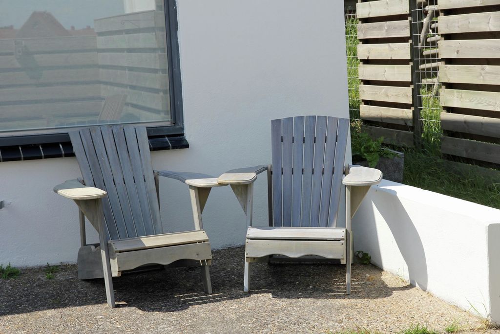 Zwei hölzerne Strandstühle an der weißen Fassade des Ferienhauses