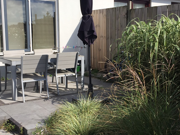 Terras met tuinmeubelen en siergrassen bij vakantiehuisje Duinzand