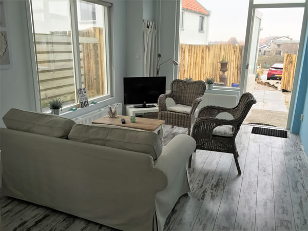 Lichte woonkamer van Duinzand met openslaande deuren naar het terras