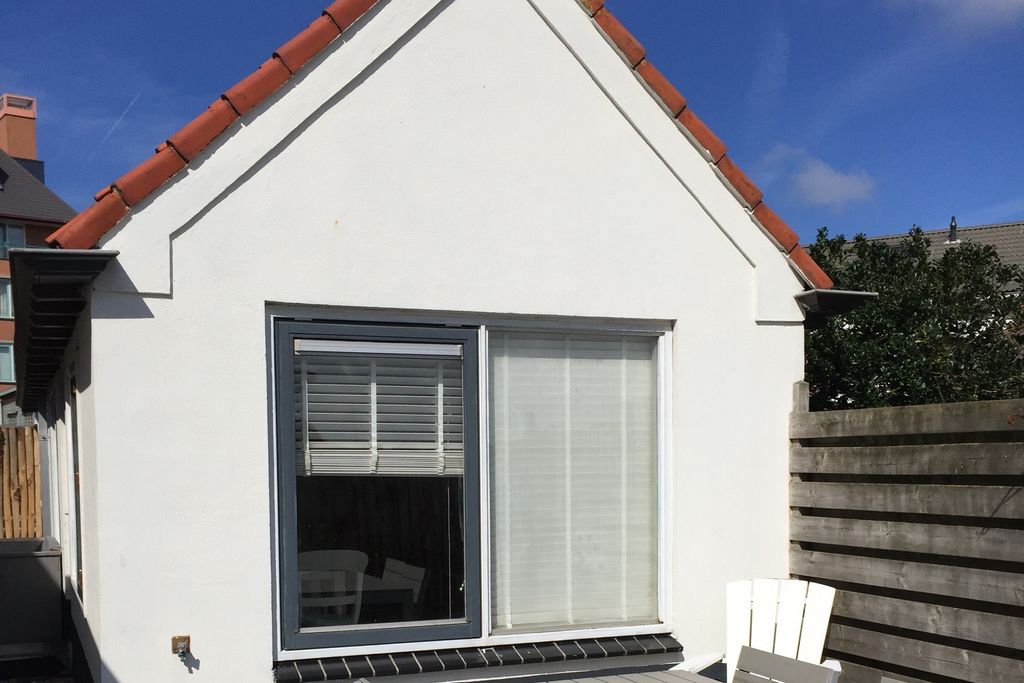 Ferienhaus Helmgras: weiße Fassade mit roten Dachziegeln unter blauem Himmel